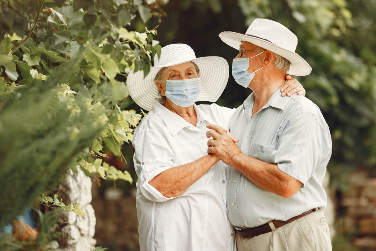 adult couple in summer garden coromavirus theme people in medical mask handsome senior in white shirt