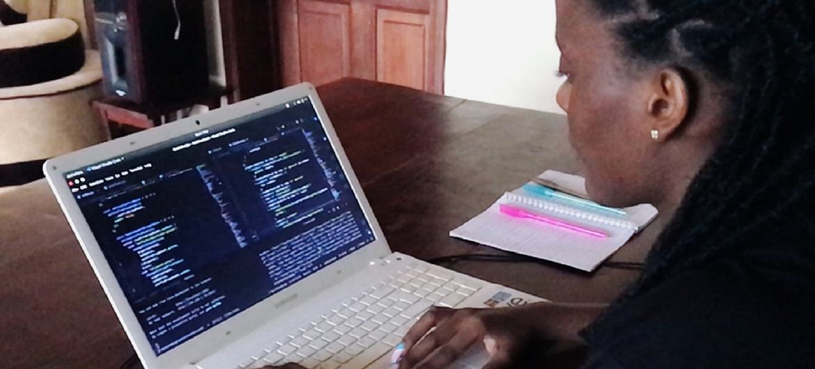 Carine, uma engenheira de software, trabalha na codificação de back-end dos aplicativos em que está trabalhando, Save and Save+ em Kigali, Ruanda.